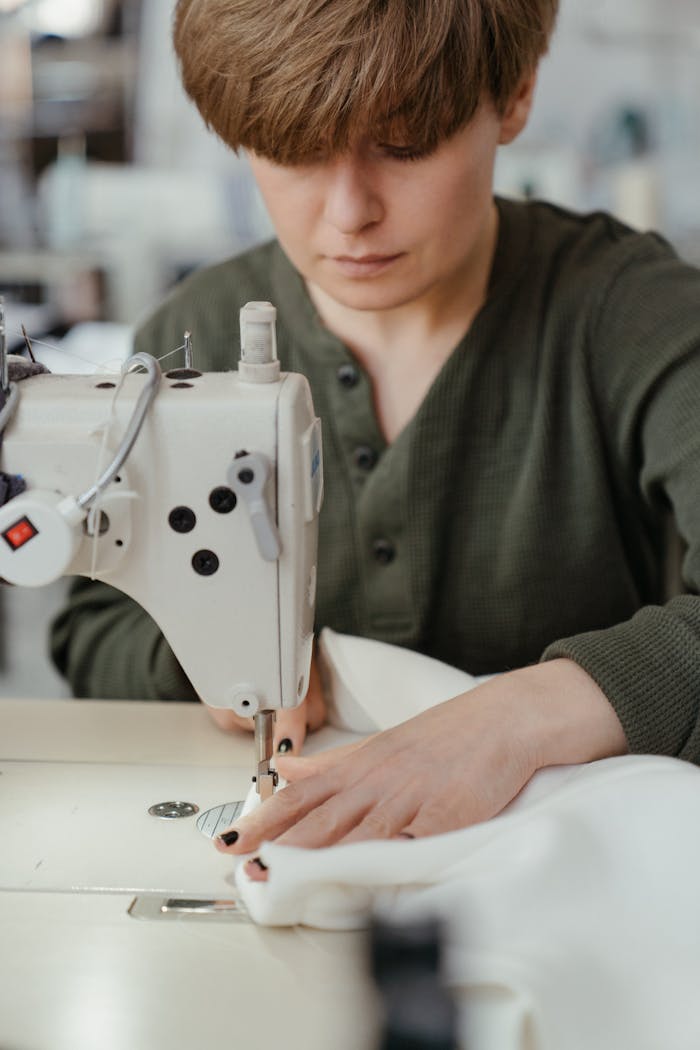A dedicated seamstress operating a sewing machine in a workshop setting, concentrating on her craft.