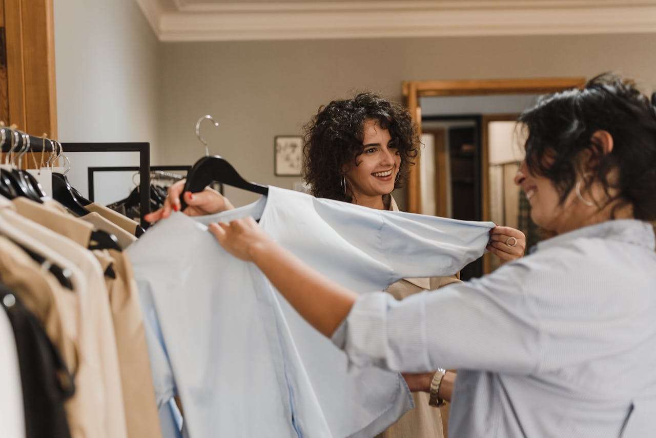 Two women cheerfully shopping for clothes in a fashionable boutique setting.
