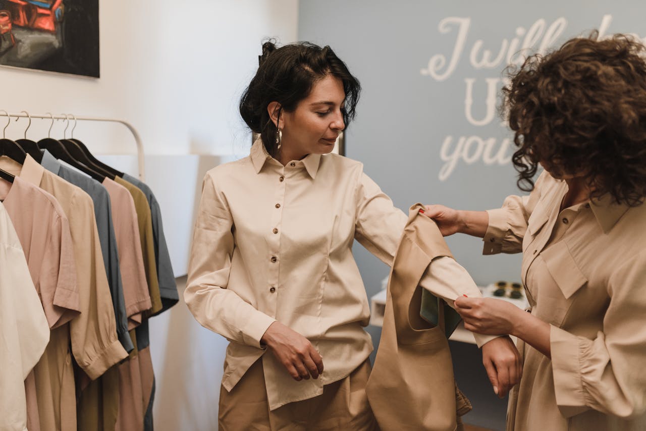 Two women shopping in a boutique, examining a shirt together amidst a stylish clothing selection.
